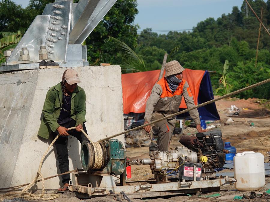 C&aacute;c c&ocirc;ng nh&acirc;n sử dụng m&aacute;y m&oacute;c để hỗ trợ đưa vật liệu l&ecirc;n tr&ecirc;n cao để thi c&ocirc;ng