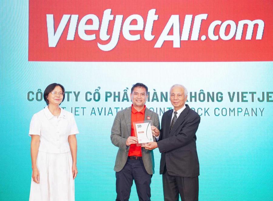 &Ocirc;ng Nguyễn An Di - Gi&aacute;m đốc Nh&acirc;n sự Vietjet (&aacute;o T - shirt đỏ, &aacute;o kho&aacute;c ghi x&aacute;m) nhận giải thưởng t&ocirc;n vinh Top 50 doanh nghiệp ph&aacute;t triển bền vững từ ban tổ chức.