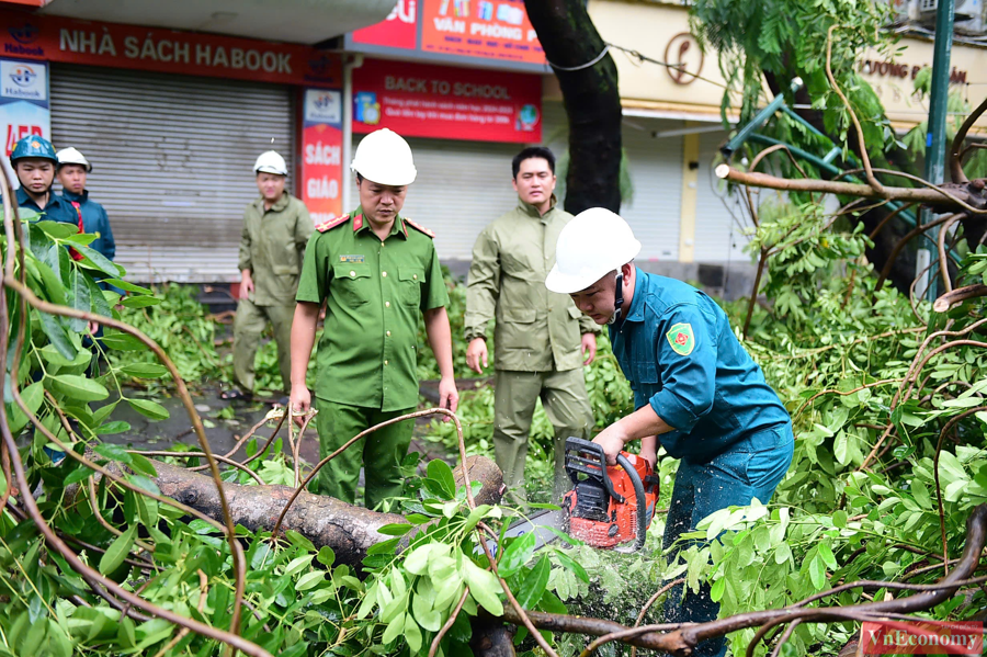 Lực lượng chức năng đang tiến h&agrave;nh cắt c&agrave;nh, xẻ c&acirc;y để thu dọn đường phố tại quận Ho&agrave;ng Mai.