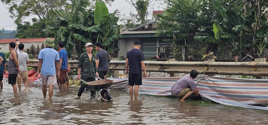 Người d&acirc;n d&ugrave;ng bao tải v&agrave; bạt để ngăn nước từ quốc lộ chảy v&agrave;o khu d&acirc;n cư