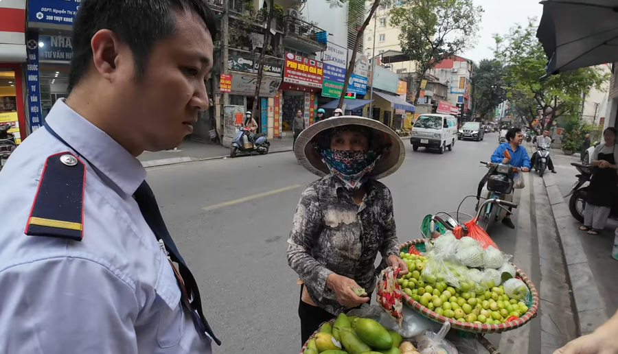 Du kh&aacute;ch người nước ngo&agrave;i su&yacute;t bị "chặt ch&eacute;m" khi mua t&aacute;o tại một g&aacute;nh h&agrave;ng rong H&agrave; Nội nếu kh&ocirc;ng được một nam nh&acirc;n vi&ecirc;n bảo vệ tới hỗ trợ.