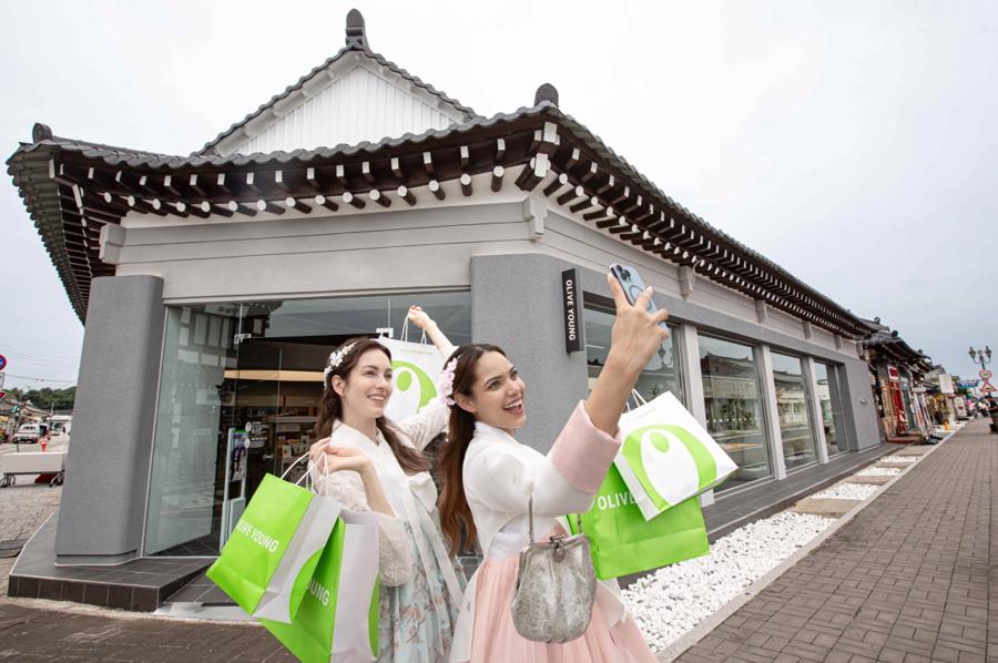 Khách hàng phương Tây chụp ảnh trước cửa hàng Olive Young ở Gyeongj, Hàn Quốc. Ảnh: Korea Herald